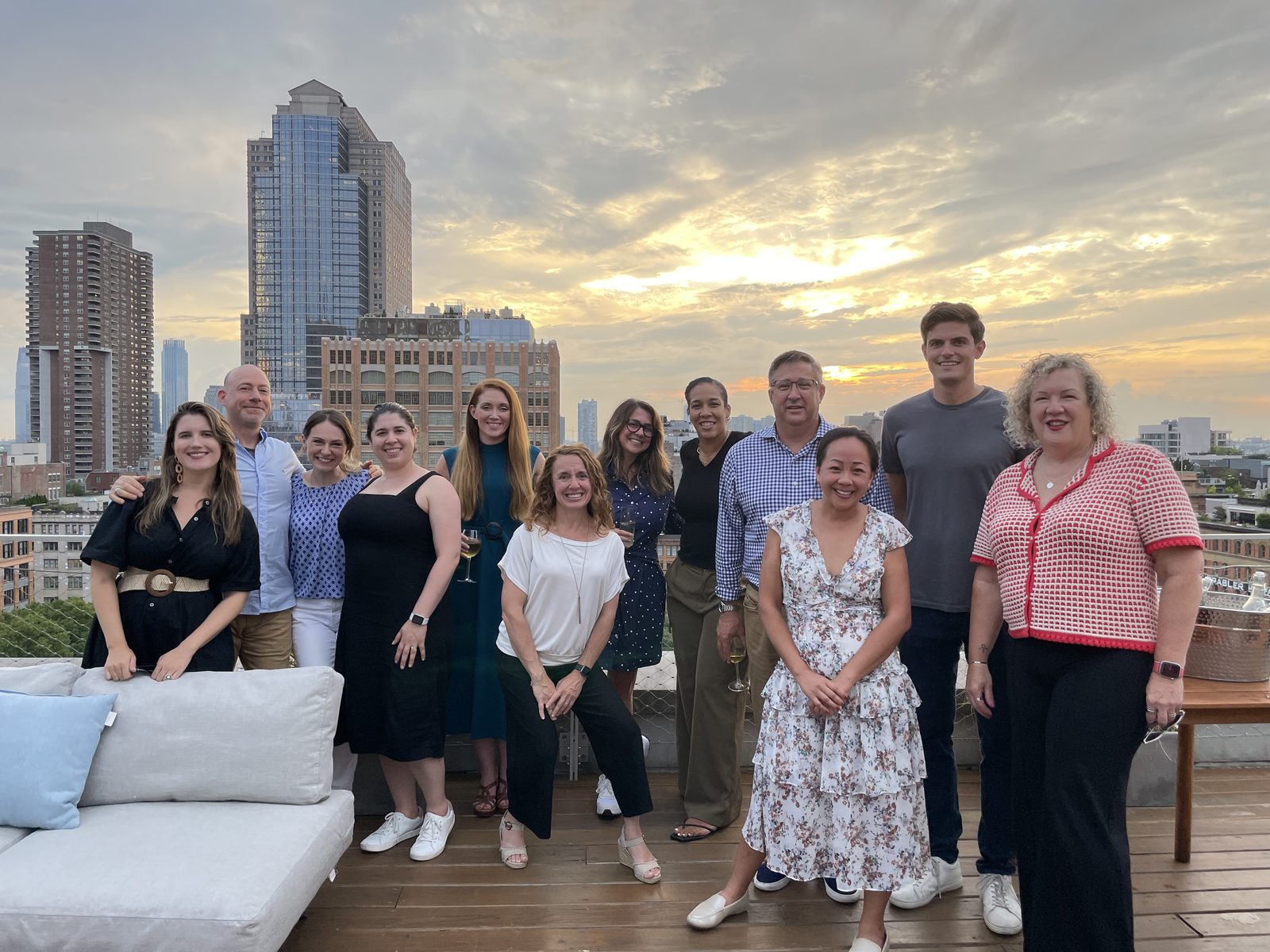 Members gathered on a New York rooftop at sunset with the city skyline behind them